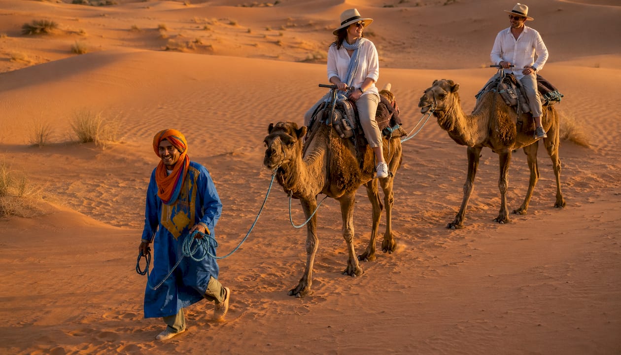 Morocco Photography Guide: Capture Every Scene Like a Pro 2 Tourists riding camels on Sahara dunes at sunset